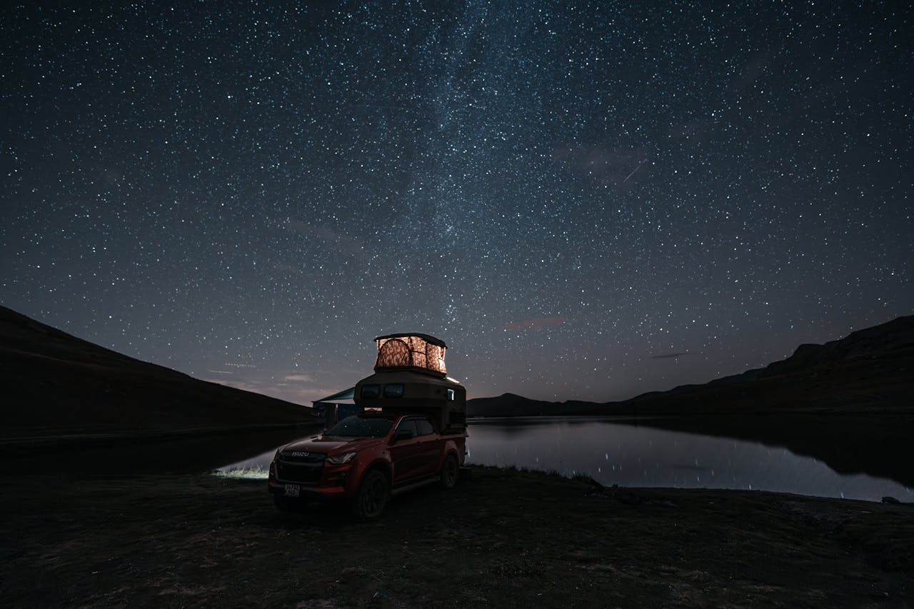 about-03 A serene camping scene with a pick-up truck under the starry sky by a lakeside in Trabzon, Türkiye.