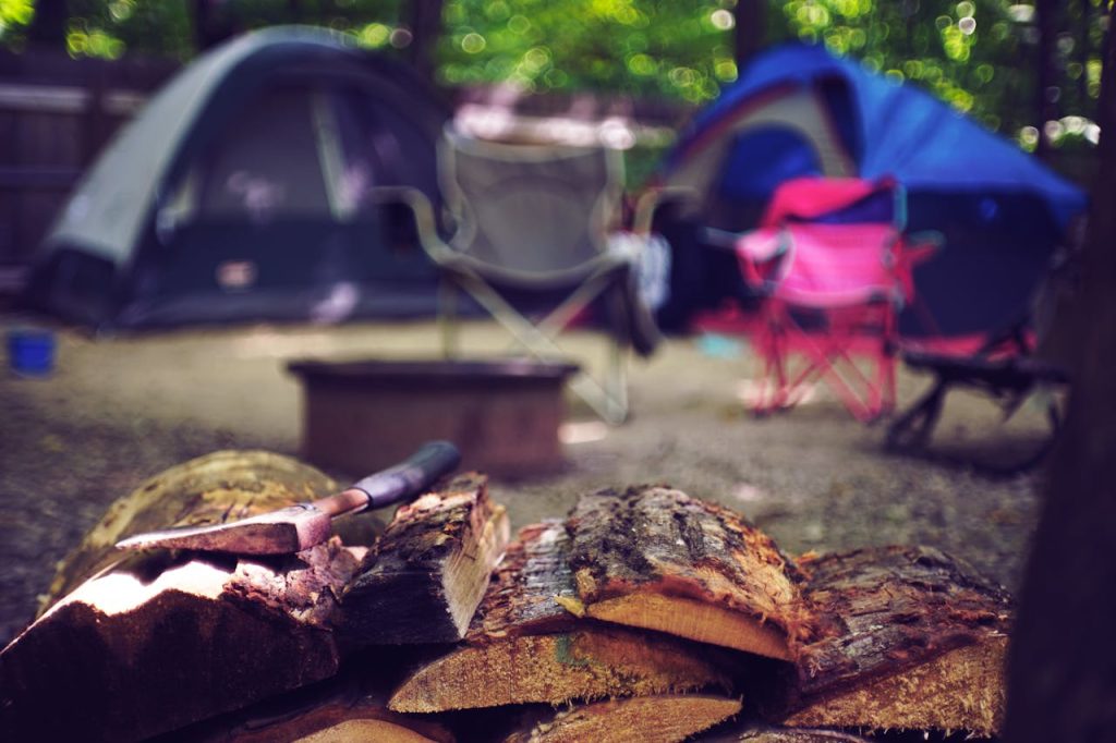 pexels-photo-2662831 A serene campsite featuring tents, chairs, and a pile of firewood for a perfect summer getaway.